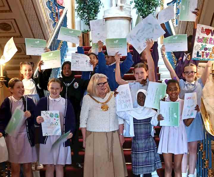 Young people stood on the steps at the town hall, holding their posters in the air, with the Lord Mayor in the centre.