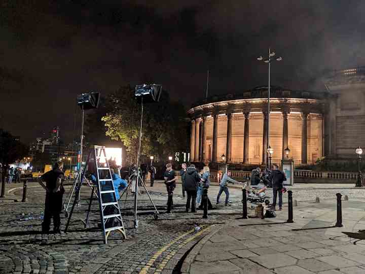 Production crew filming on William Brown Street in the evening