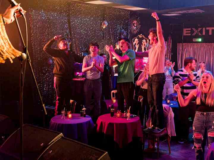 Young men in a pub setting cheering.