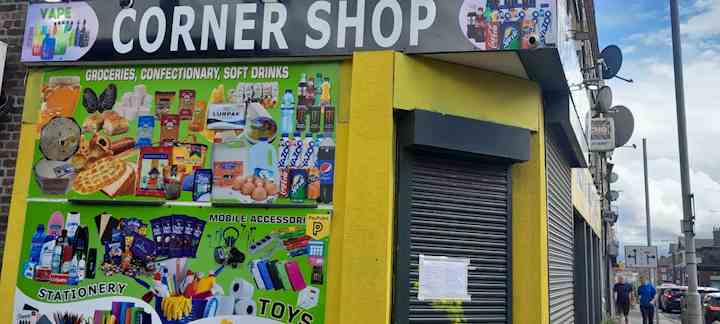 A shop front with the shutters closed. Taped to the shutters is a paper closure notice